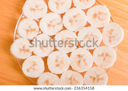 peeled and sliced banana slices on a glass plate on a yellow table top view