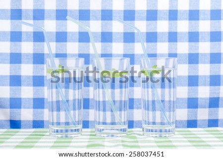glass of clean water with mint on a table covered with  checkered napkin