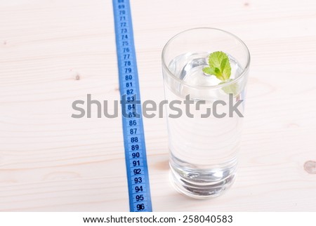 glass of clean water with mint on a table next to  centimeter diet
