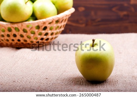 Green apple in the foreground, in the background basket with apples
