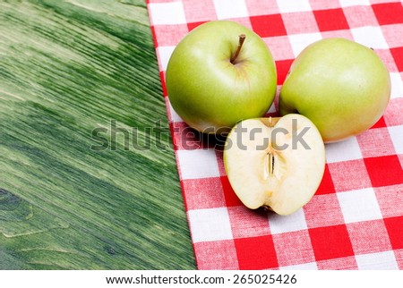 Two green apples and cut apple on a green table, top view