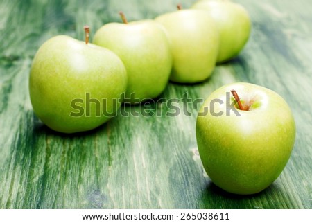 One green apple in the foreground, on a background of apples in a row