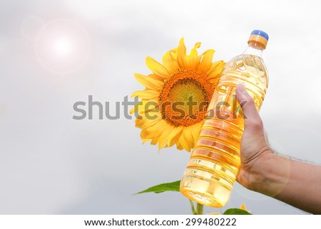 Bottle of sunflower oil in his hand on  background of sunflowers and sun