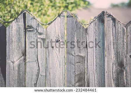 old wooden fence with barbed wire on top. Vintage photography effect.