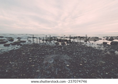 rocky sea beach with wide angle perspective over the sea clouds - retro, vintage style look