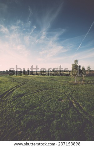 country landscape with fields and blue sky with plane trails - retro, vintage style look