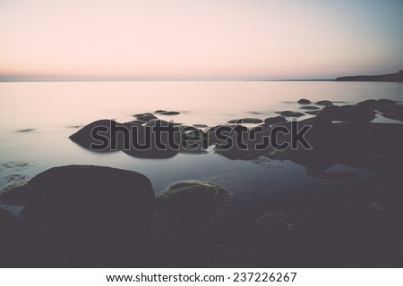 rocky beach at sunset with milky water - retro, vintage style look