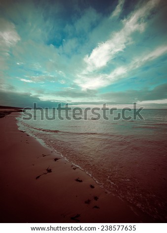 baltic beach in fall with clouds and waves towards deserted dunes. cloudy day - vintage 80\'s retro color film look