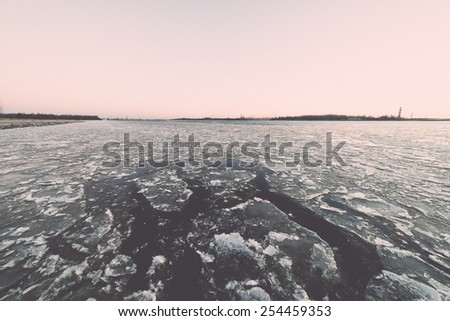 sunset over frozen sea with ice blocks and dramatic colorful sky - vintage retro grainy film effect