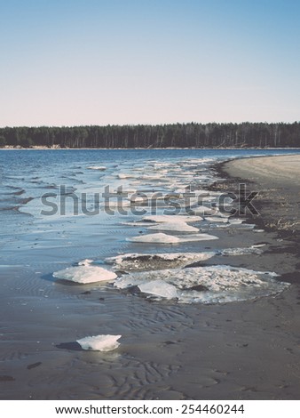 frozen sea beach with blue sky and snow covered tracks - retro vintage effect
