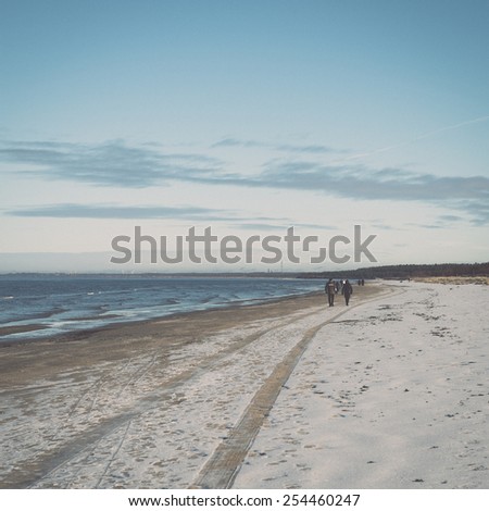 frozen sea beach with blue sky and snow covered tracks - retro vintage effect