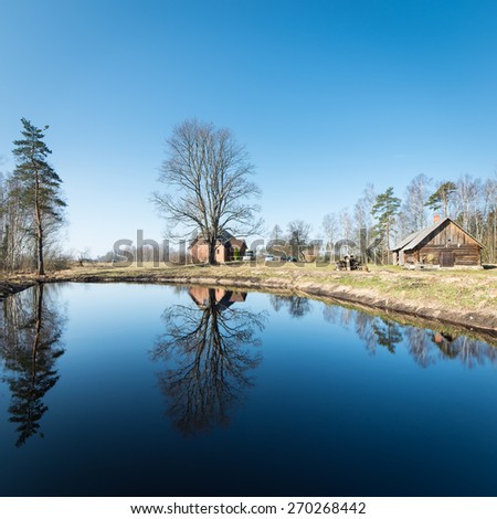 reflections of country house in the pond with trees and blue sky