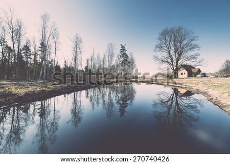 reflections of country house in the pond with trees and blue sky - retro vintage film effect