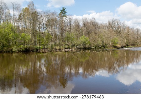 scenic and beautiful reflections of trees and clouds in water of the river