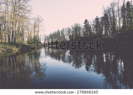 scenic and beautiful reflections of trees and clouds in water of the river - vintage effect