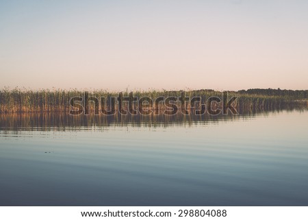 symmetric reflections on calm lake water with forests and islands - retro vintage effect