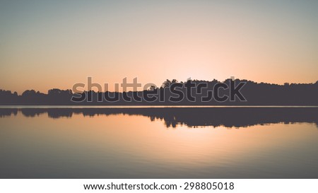 symmetric reflections on calm lake water with forests and islands - retro vintage effect
