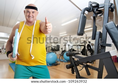 Large happy fitness man with weight scale in a gym