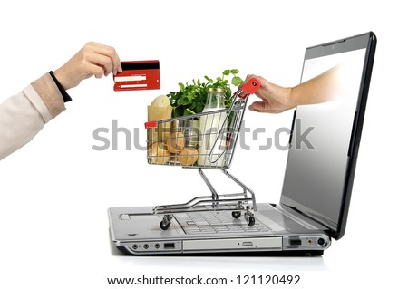 Hand with credit card and a small shopping cart coming from laptop screen isolated in white Hand with credit card and a small shopping cart coming from laptop screen isolated in white