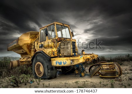 Big and old construction truck with a dark cloudy sky