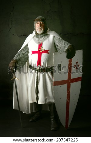 Knight Templar posing with sword in a dark background