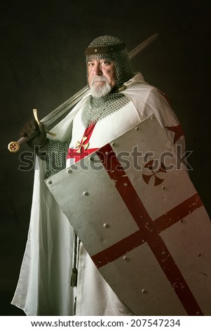 Knight Templar posing with sword in a dark background