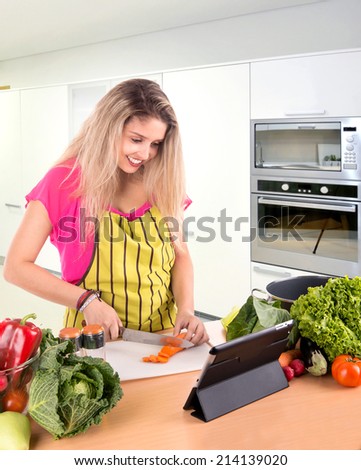 Beautiful woman cooking with tablet for recipes