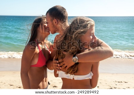 Teenage boy holding girl friend and kissing another girl