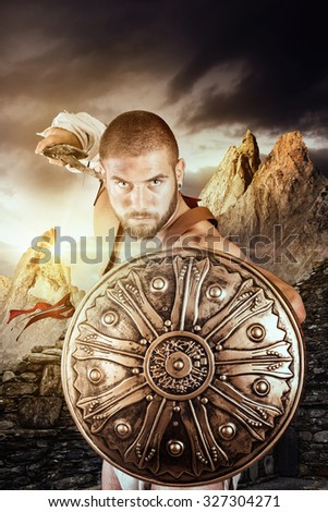Gladiator or warrior posing with shield and sword outdoors ready for battle