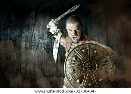 Gladiator or warrior posing with shield and sword battling in a dark forest