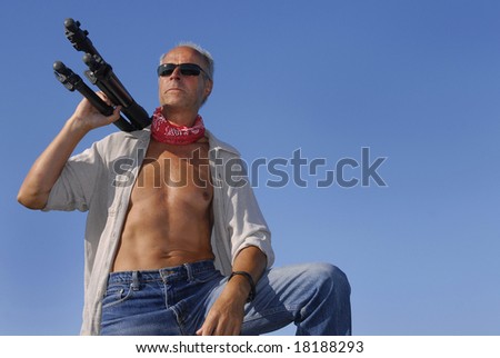 Handsome adventurer mature man, outdoors with a tripod