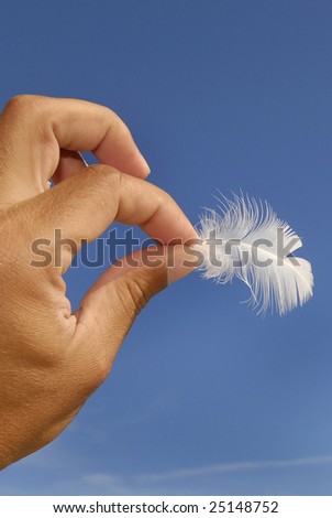 Hand holding a feather against a blue sky