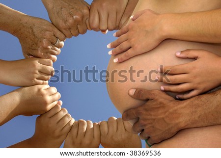 Several hands holding together around a pregnant's belly