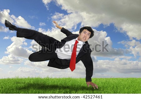 Businessman jumping in a green field