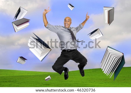 Happy businessman jumping outdoors with books all around