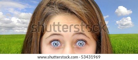 Young girl with planet eyes over a green field with blue cloudy sky