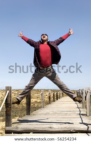 Happy man jumping outdoors with sunglasses