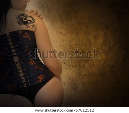 Sexy woman with corset and dragon tattoo in a grunge background