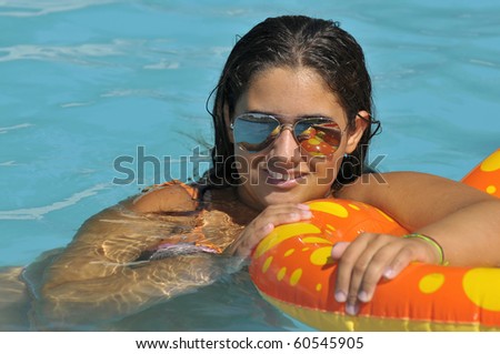 Beautiful girl posing in a swimming pool with sun glasses
