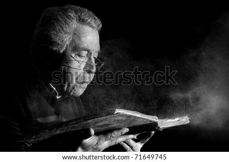 Senior man blowing dust of  a very old book in black & white