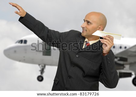 Businessman with paper plane and a jet plane passing behind