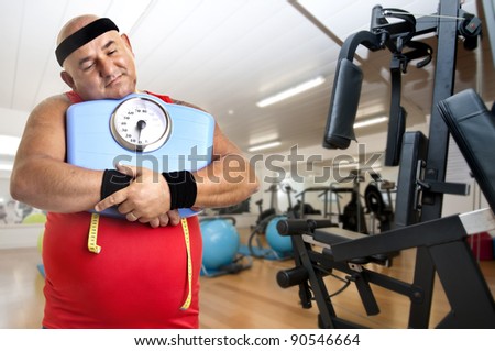Large fitness man with weight scale in the gym