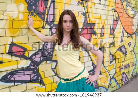 Portrait of a young beautiful girl on a background of graffiti on a brick wall