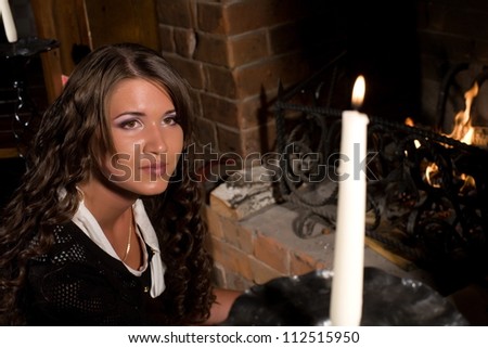 Girl sitting by the fireplace and looks at a candle