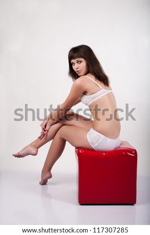 Woman in underwear sitting on a red cube