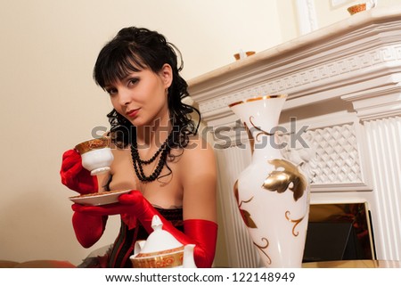 Young brunette drinking tea while sitting by the fireplace