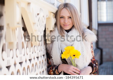 Girl with yellow flowers on a background of carved facade of the house