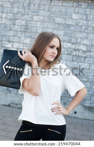 Business woman with clutch bag on a background of a stone wall