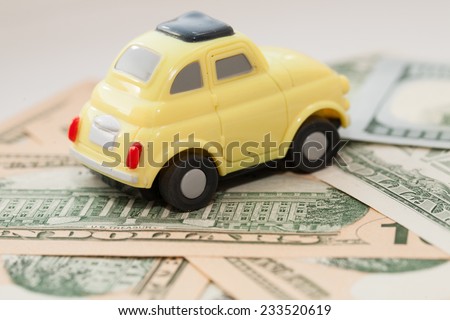 Toy car on a background of US dollars banknotes