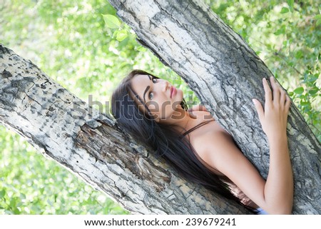 Girl with long hair peeking out from behind a tree